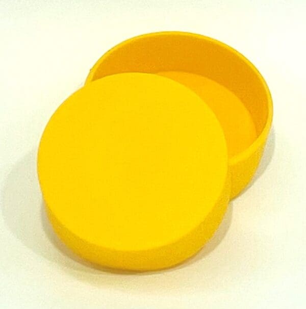 A yellow round container with lid on top of white surface.