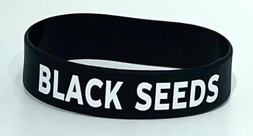 A black seed bracelet is shown on top of a table.