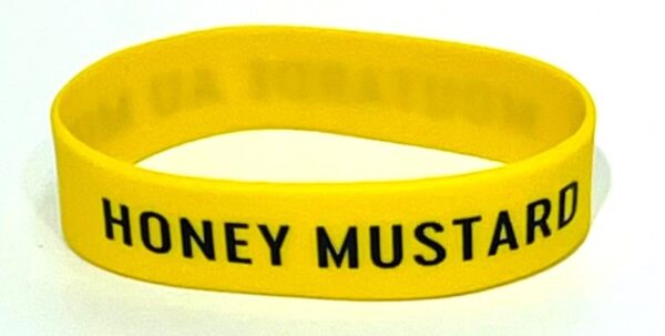 A yellow wristband with the words honey mustard written on it.