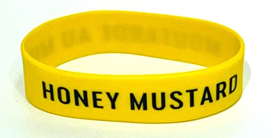 A yellow wristband with the words honey mustard written on it.