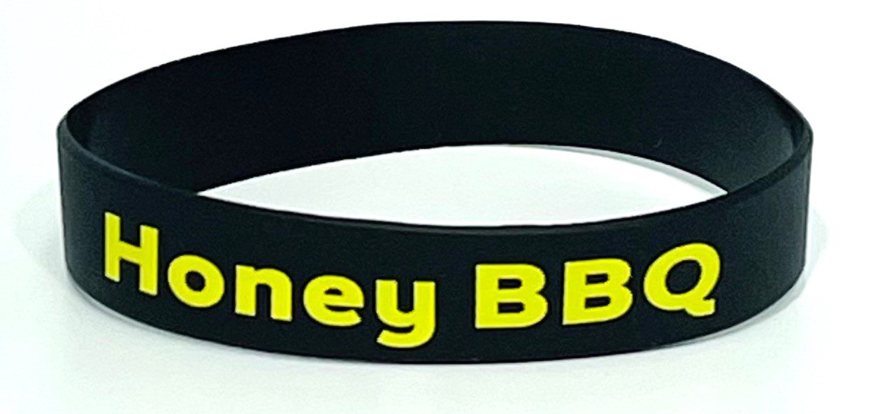 A black and yellow wristband with the words " honey bbq ".