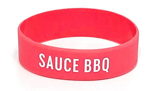 A red bracelet with the words " sauce bbq ".