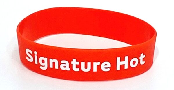 A red wristband with the words signature health written on it.