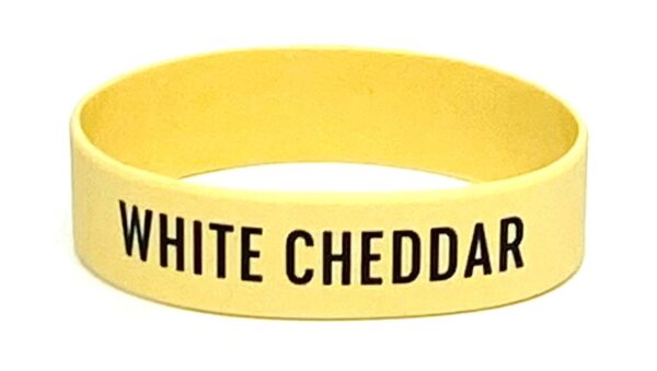 A yellow wristband with the words " white cheddar " written on it.