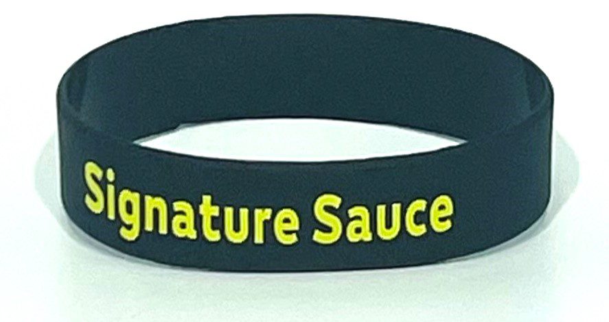 A black wristband with the words " signature sauce ".