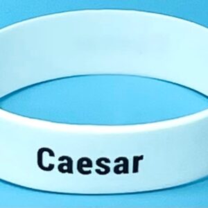 A white wristband with the word caesar written on it.