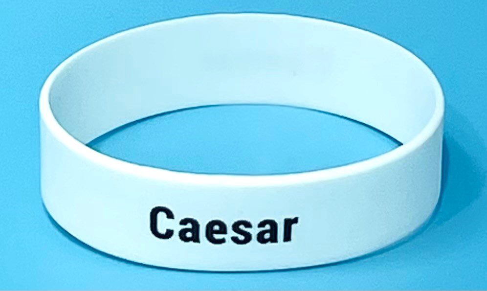 A white wristband with the word caesar written on it.