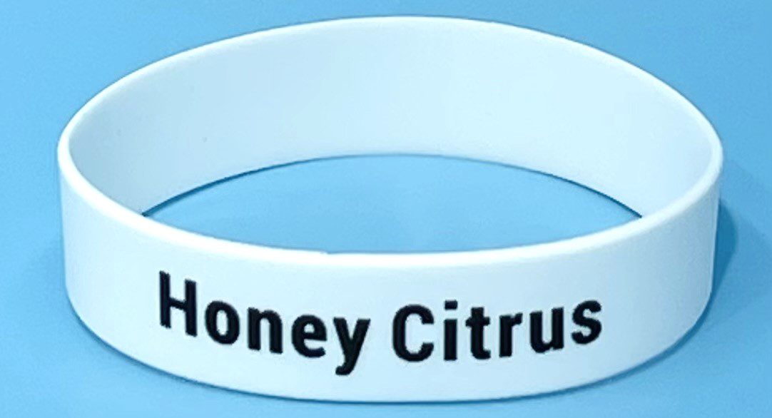 A white wristband with the words honey citrus on it.