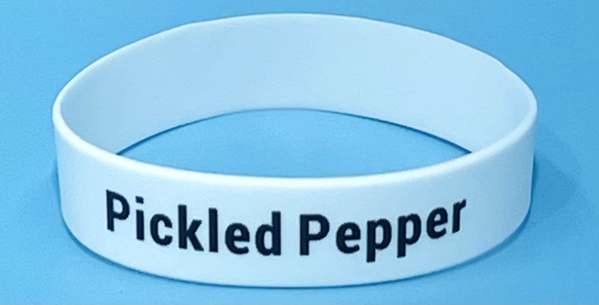 A white bracelet with the words " tickled pepper ".