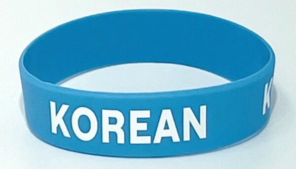 A blue wristband with the word " korean " written on it.