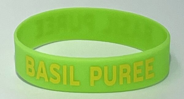 A green bracelet with the words " basil pure " written on it.