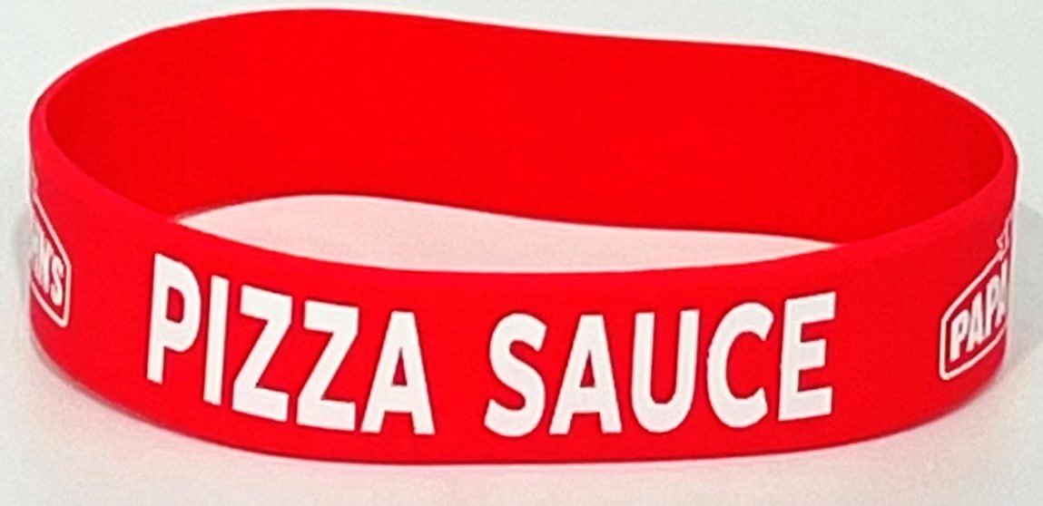 A red wristband with the words " pizza sauce " written on it.