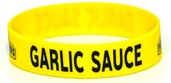 A yellow bracelet with the words garlic sauce written on it.