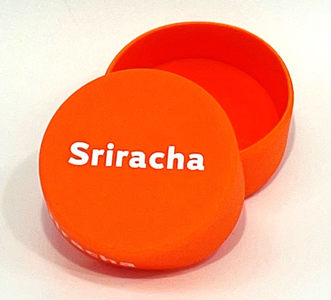 A round orange box with the name sriracha on it.