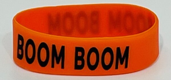 A neon orange rubber bracelet with the words boom boomin on it.