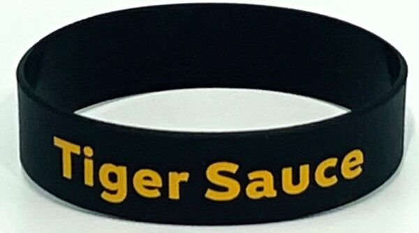 A black and yellow wristband with the words tiger sauce written on it.