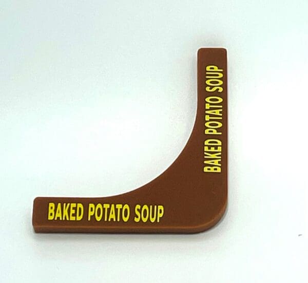 A brown plastic wedge shaped sign with baked potato soup written on it.