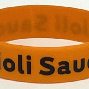 A close up of an orange bracelet with the words " holi sauda ".