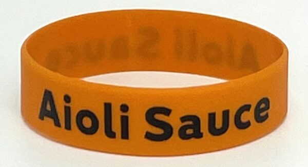 A close up of an orange bracelet with the words " holi sauda ".