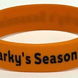 A close up of a wristband with the words " sparky 's season."