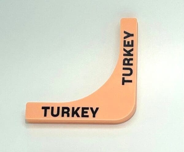 A turkey shaped plastic sign on a white surface.