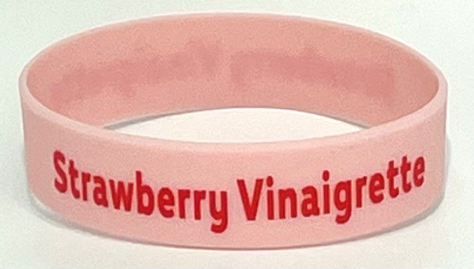 A pink bracelet with the words strawberry vinaigrete on it.