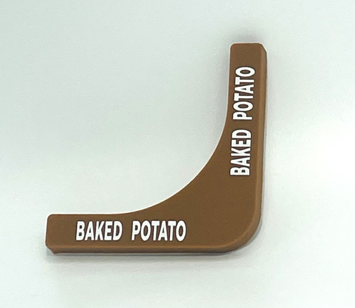 A brown wedge shaped object with the words baked potato written on it.