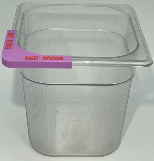 A plastic container with pink handle on top of table.