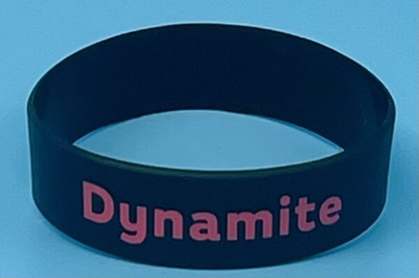 A black wristband with the word dynamite written on it.