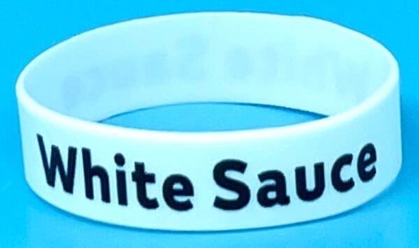 A white bracelet with the words " white sauce ".