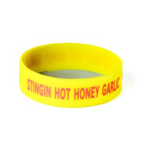 A yellow wristband with the words stingin hot honey garlic written on it.
