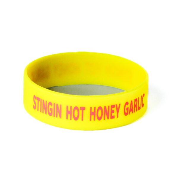 A yellow wristband with the words stingin hot honey garlic written on it.