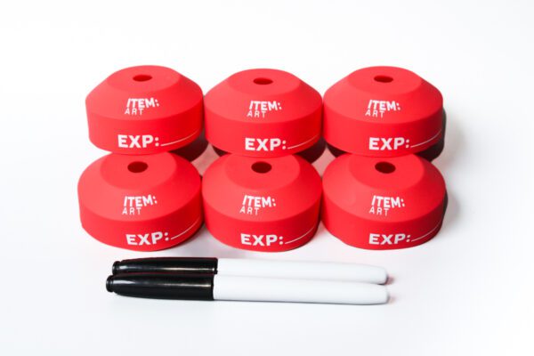 A group of six red caps sitting next to two white markers.