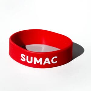 Red wristband with "SUMAC" in white letters.