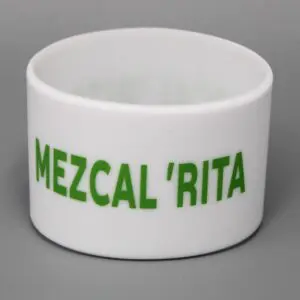White cup with "MEZCAL 'RITA" in green.
