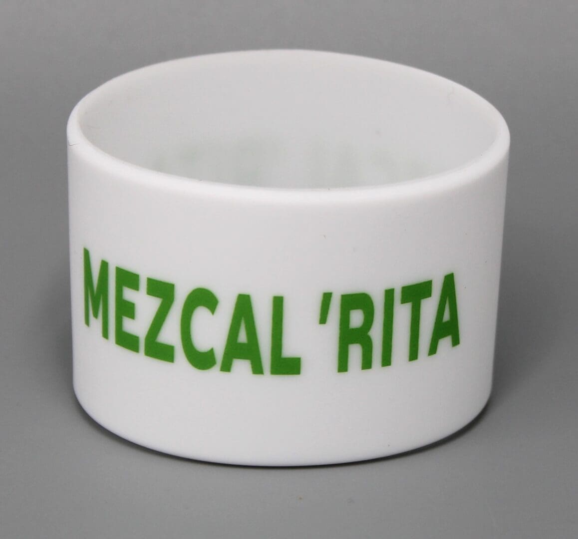 White cup with "MEZCAL 'RITA" in green.