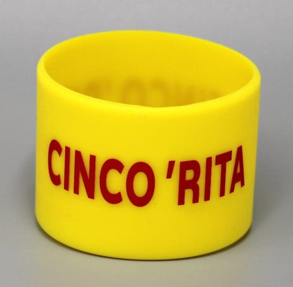 Yellow bracelet with "CINCO 'RITA" in red.