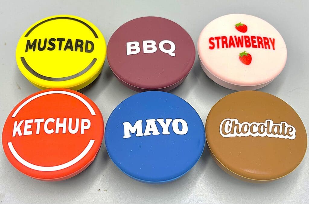 Colorful condiment caps labeled with mustard, BBQ, strawberry, ketchup, mayo, and chocolate.